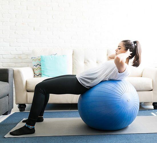 A girl training on a fitness ball at home